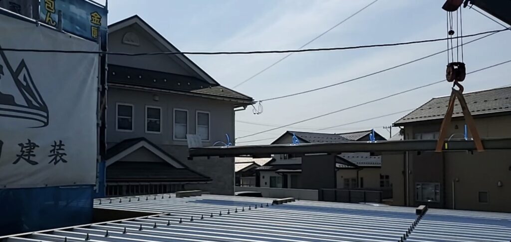 クレーン付き車両で屋根材を荷揚げ。
